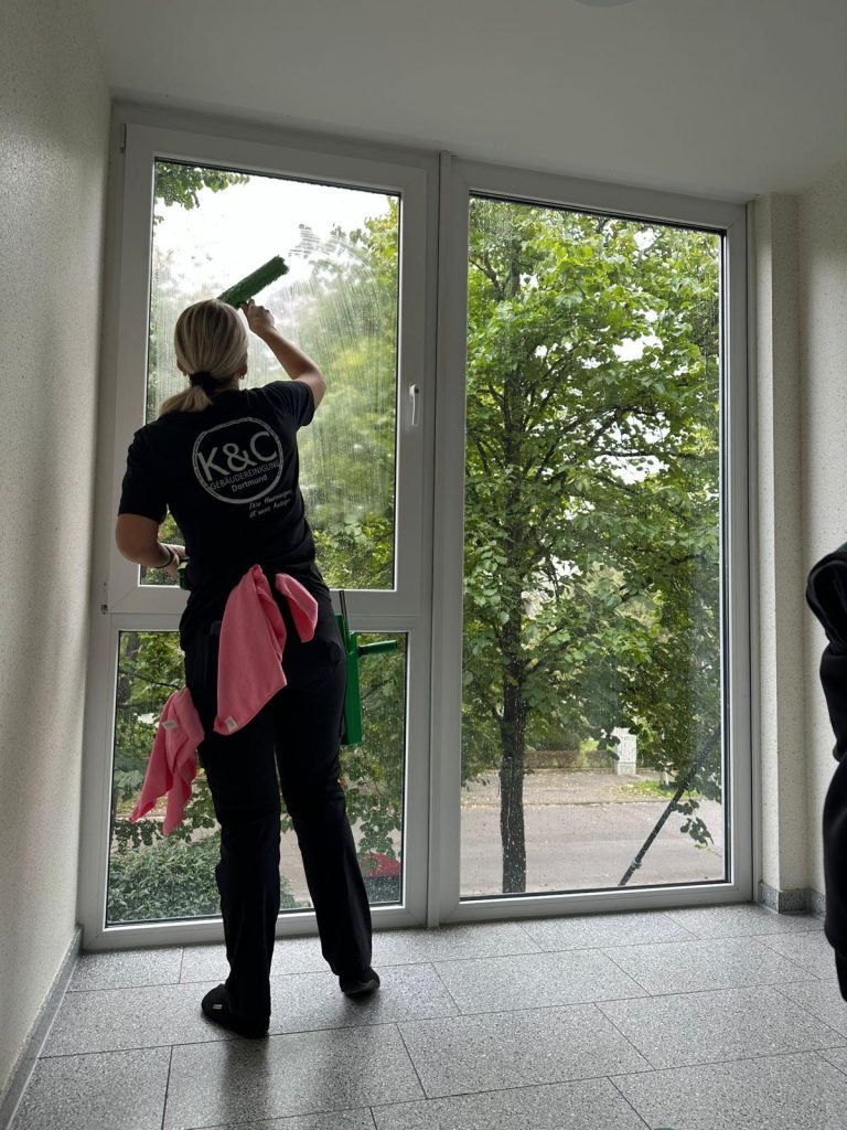 Mitarbeiterin von K&C Gebädeureinigung bei der Glasreinigung eienr Fensterscheibe