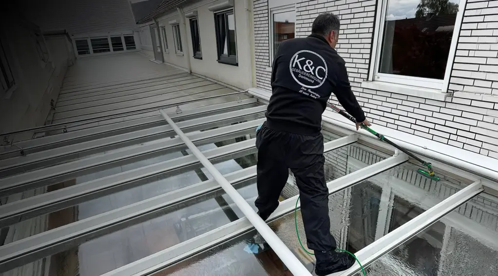 Foto eines Mitarbeiters von K&C bei der Reinigung eines Terrassenvordachs.