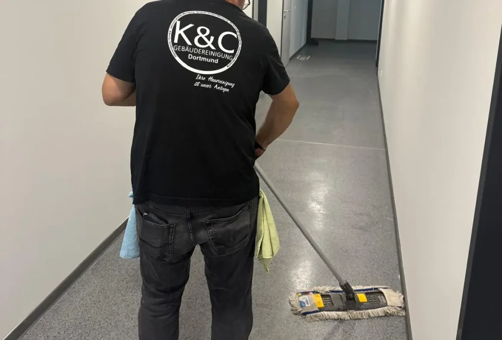 Nahaufnahme eines Mitarbeiters beim Wischen eines Flurs.