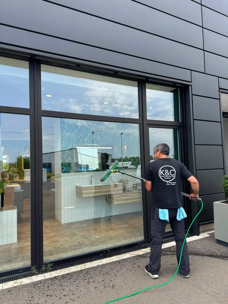 Foto eines Mitarbeiters von K&C bei der Glasreinigung einer Scheibe eines Ladenlokals.